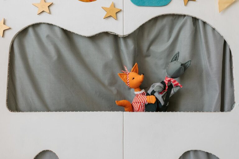 Bright puppet theater setup with two animal puppets performing on stage.