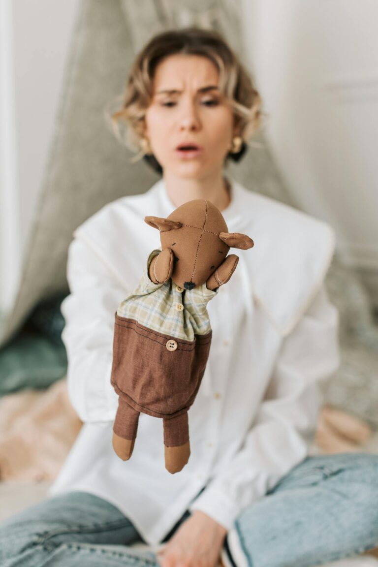 Woman performing puppetry with a handmade brown puppet indoors, ideal for entertainment and storytelling concepts.